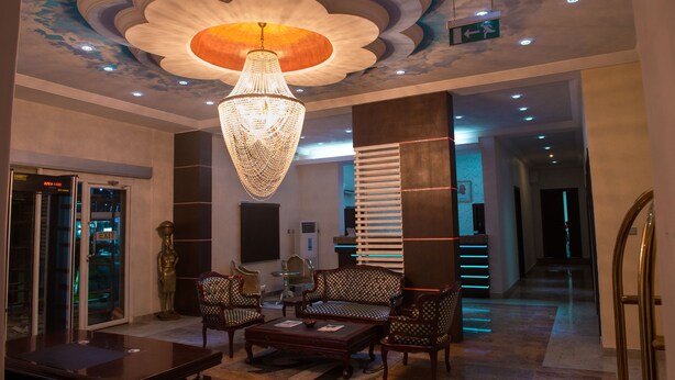 A lobby with a chandelier, seating area, and a reception desk.