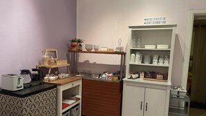 A compact kitchenette with a toaster, kettle, and coffee maker on the counter, a small sink, and a cabinet with dishes and utensils. - Hotell Sta Clara (Sundsvall)