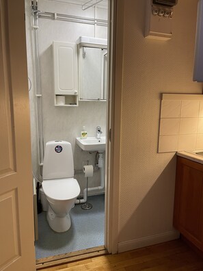 A compact bathroom with a toilet, sink, and cabinet. - Hotell Sta Clara (Sundsvall)