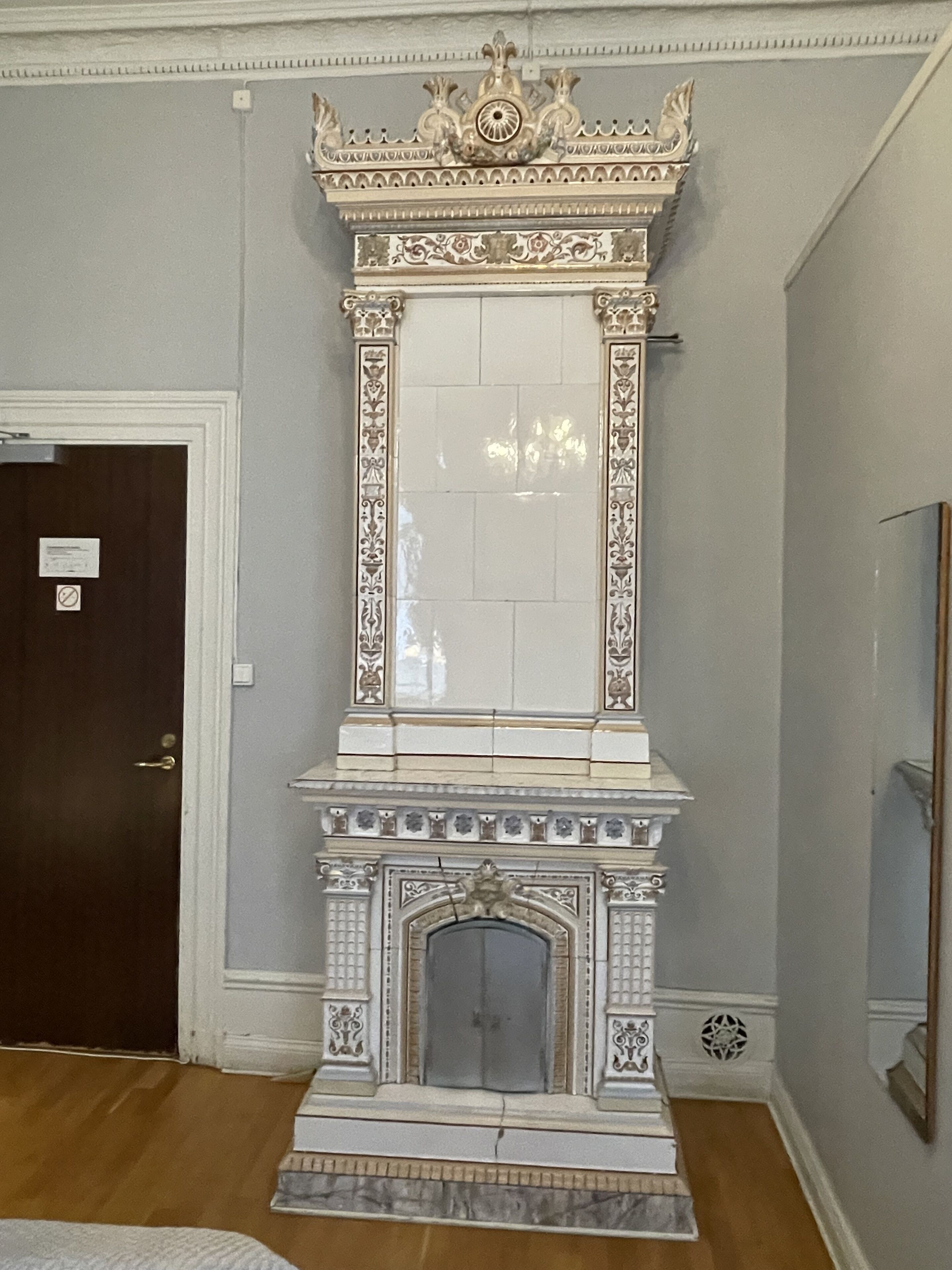 Una habitación con chimenea, una puerta y un espejo en la pared.