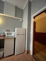 Una cocina compacta con microondas, refrigerador y una pequeña encimera.