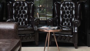 A room with two leather armchairs, a small round table, and a sofa. - Wall Street - Maestro (Odesa)