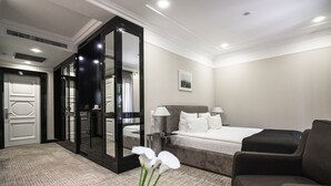 A hotel room with a large bed, a sitting area, a mirror, and a door leading to a bathroom. - Wall Street - Maestro (Odesa)