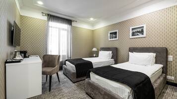 Une chambre d’hôtel avec deux lits, un bureau, une chaise, une télévision et une fenêtre avec des rideaux.