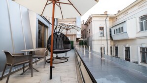 A balcony with outdoor furniture, including chairs and a table, and a large umbrella providing shade. - Wall Street - Maestro (Odesa)