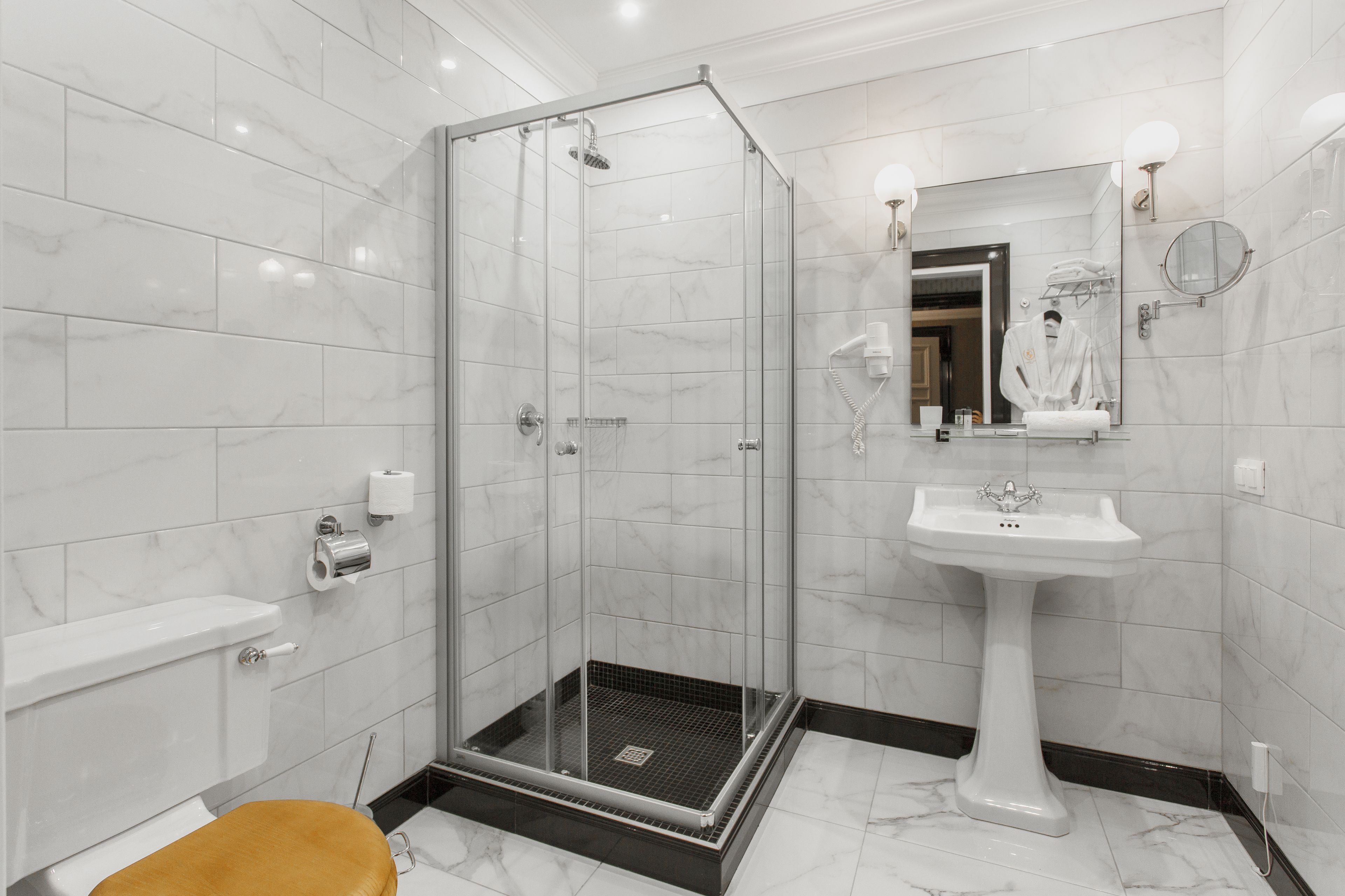Ein modernes Badezimmer mit einer Duschkabine, einem Waschbecken auf Säule und einer Toilette.