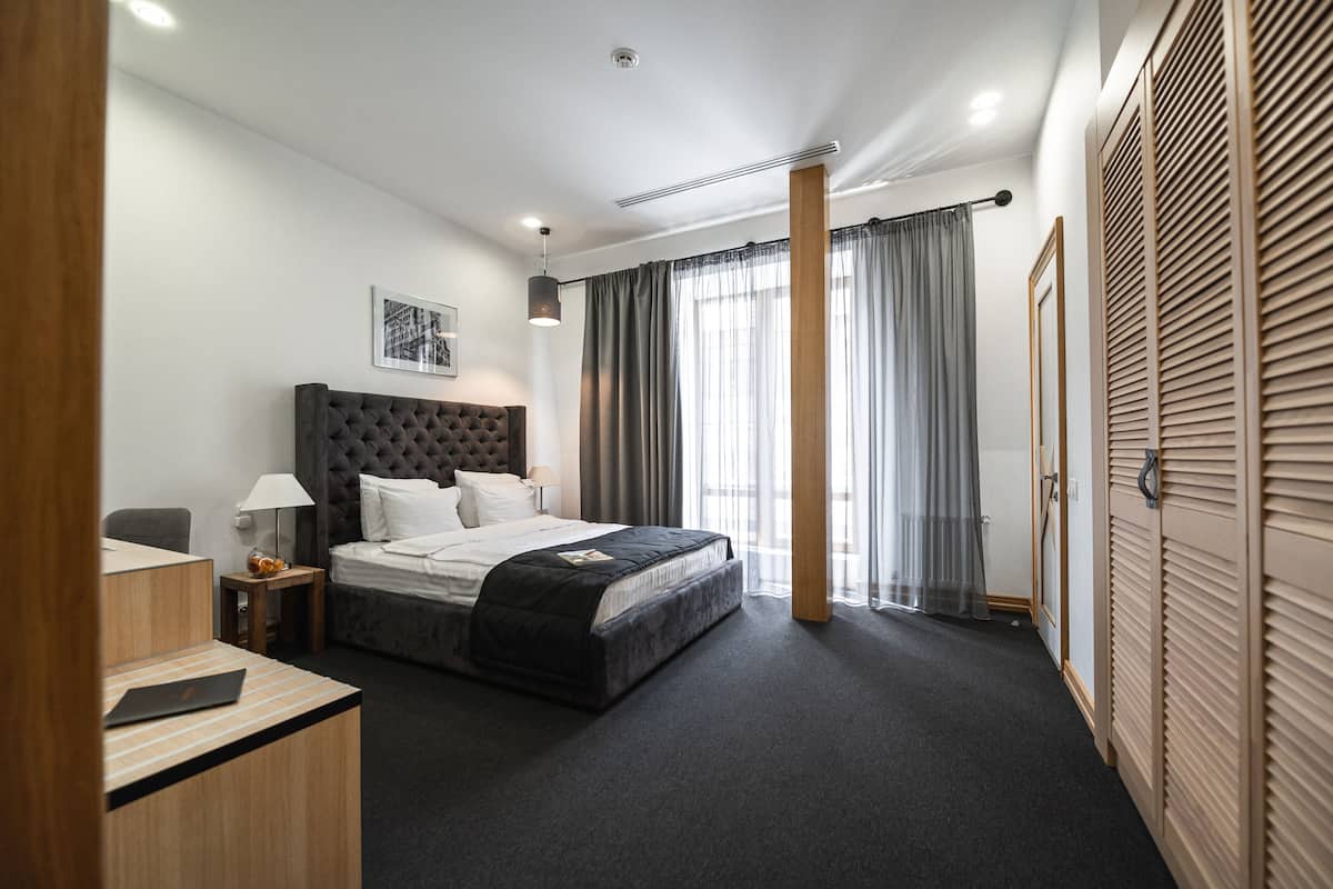 Una habitación de hotel moderna con una cama grande, un escritorio, una silla y un armario.