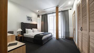 Una habitación de hotel moderna con una cama grande, un escritorio, una silla y un armario.