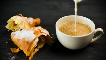 A cup of coffee with a pastry on a dark surface.