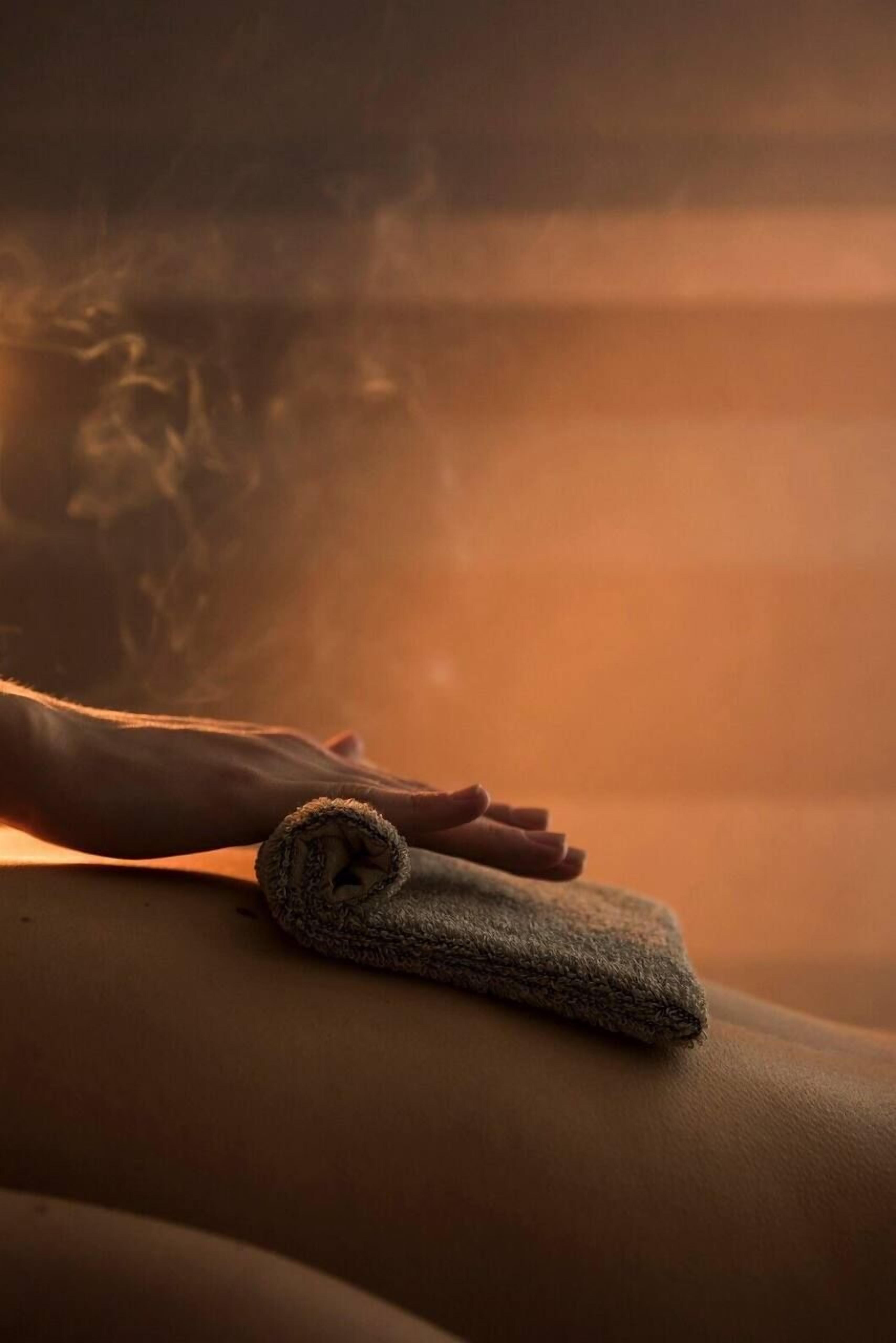 A person receiving a massage with a towel on their back.