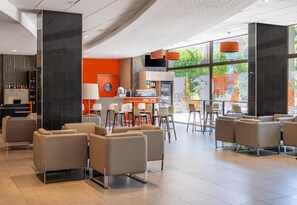 A modern hotel lobby with seating areas, a bar, and a view of the outdoors. - Spark by Hilton Lyon Park Saone (Lyon)