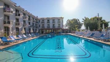 Una piscina con sillas de descanso y un edificio con balcones.