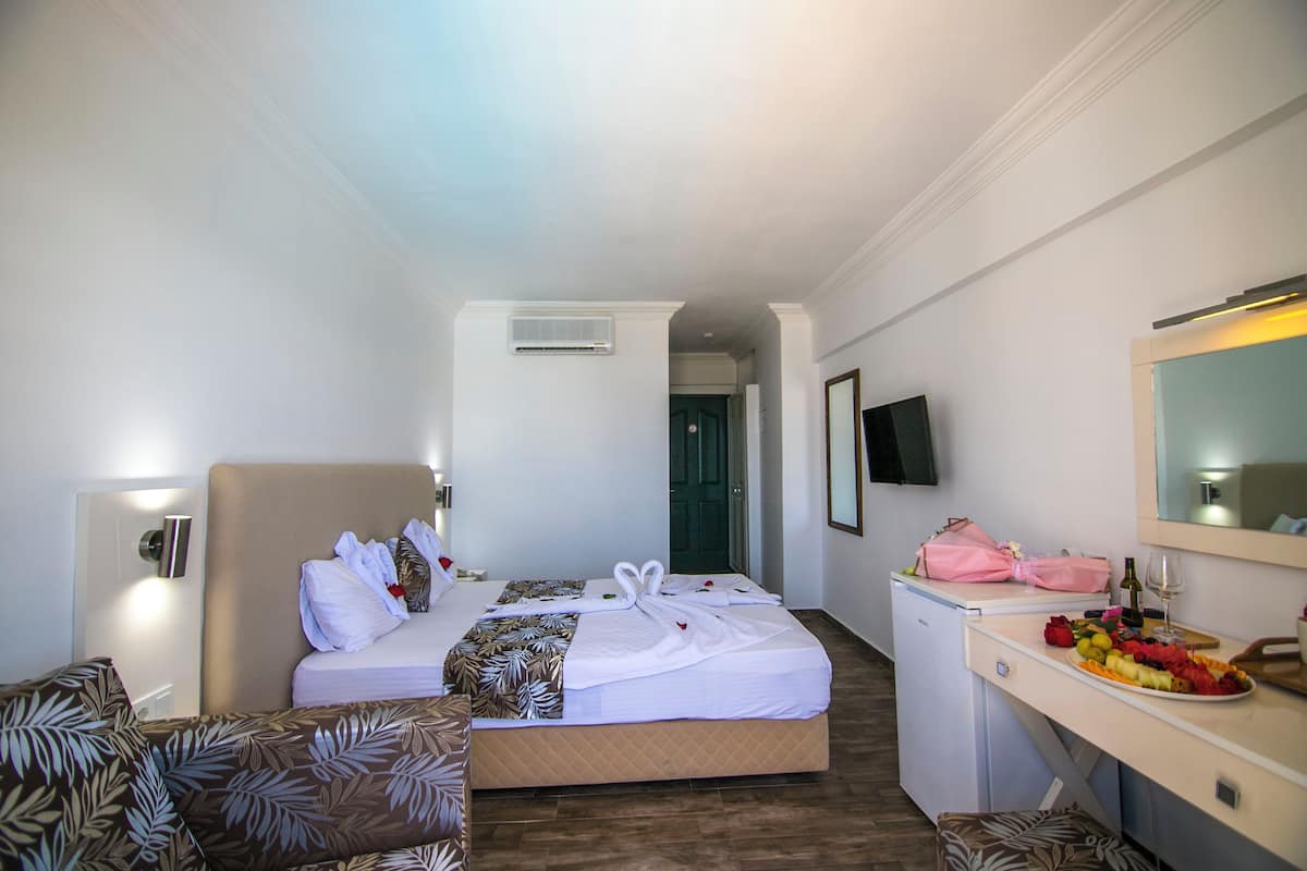 Una habitación de hotel con cama, escritorio, silla y una pequeña kitchenette.