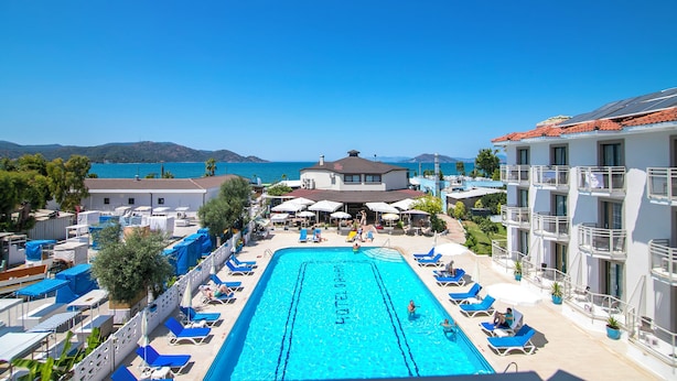 A hotel pool with a clear view of the sea, lounge chairs, and umbrellas. - Bahar Hotel (+12 Adult ) (Fethiye)