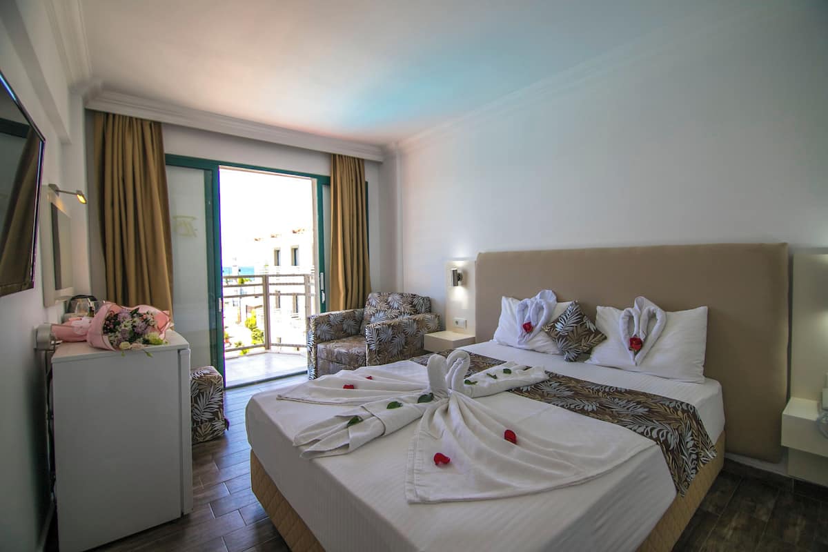 Una habitación de hotel con cama, una silla, un escritorio y un balcón.