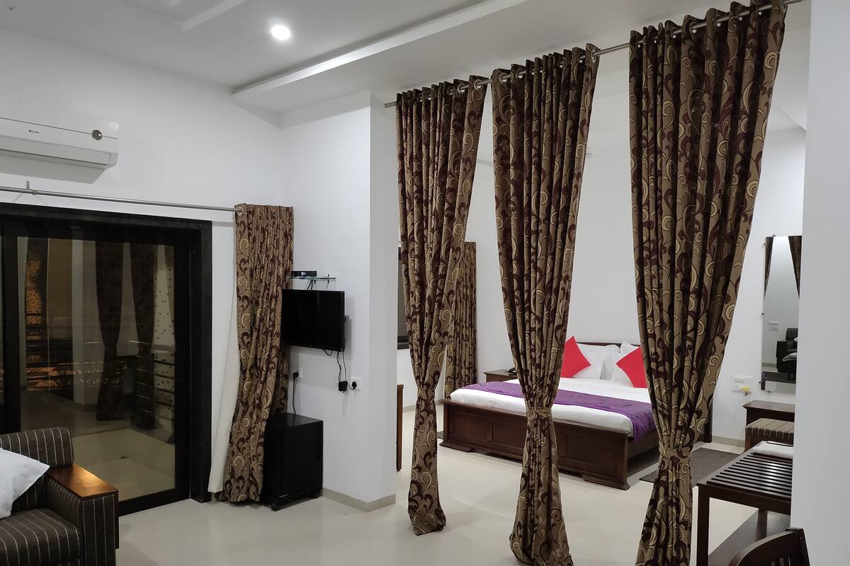 Een hotelkamer met een bed, een aan de muur bevestigde televisie, een bureau en een stoel.