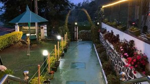 A pathway leading to a gazebo with hanging planters and potted plants on either side. - Royal Mount Hotel (Nuwara Eliya)