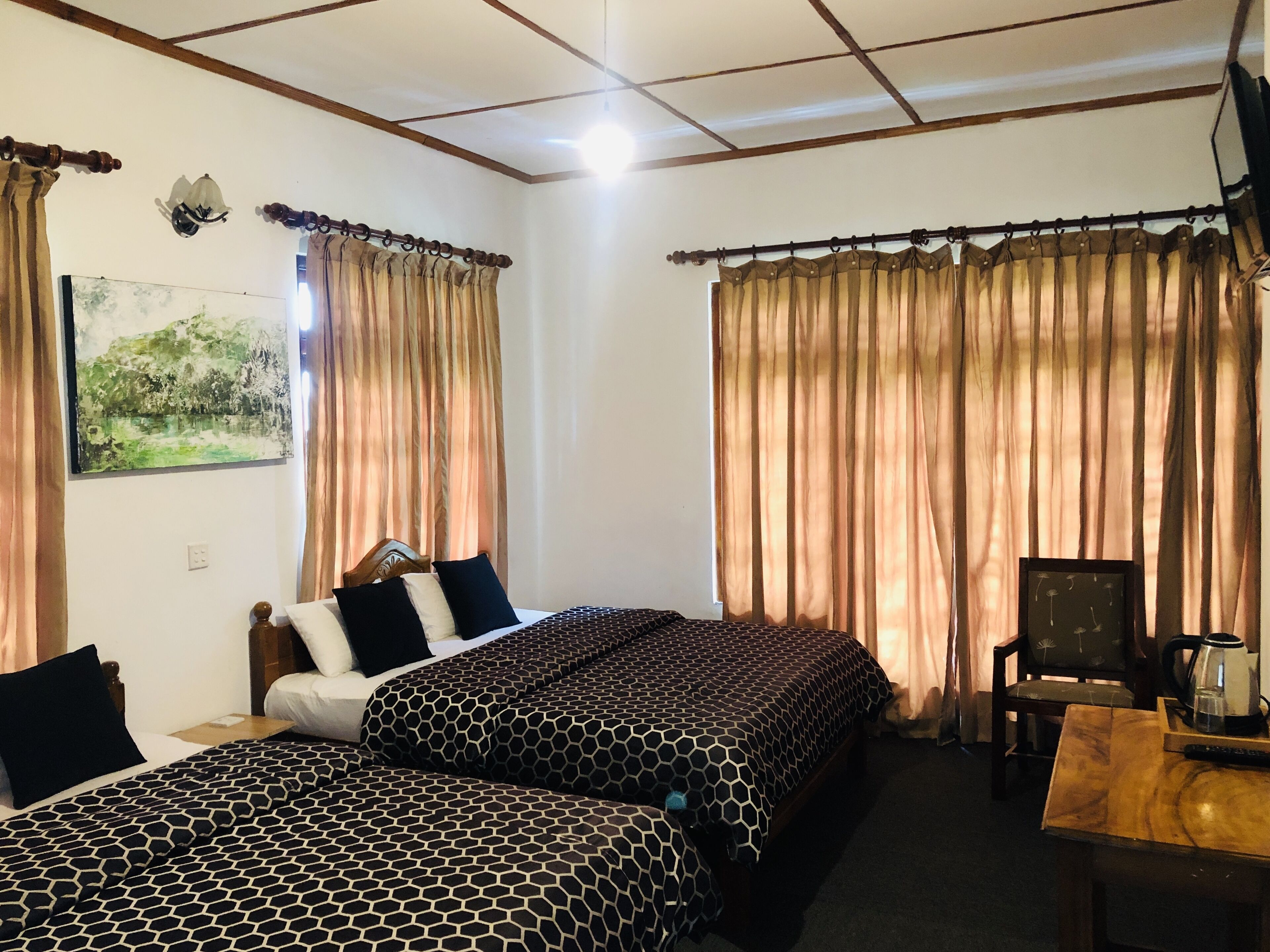 A hotel room with two beds, a chair, a table, and curtains.