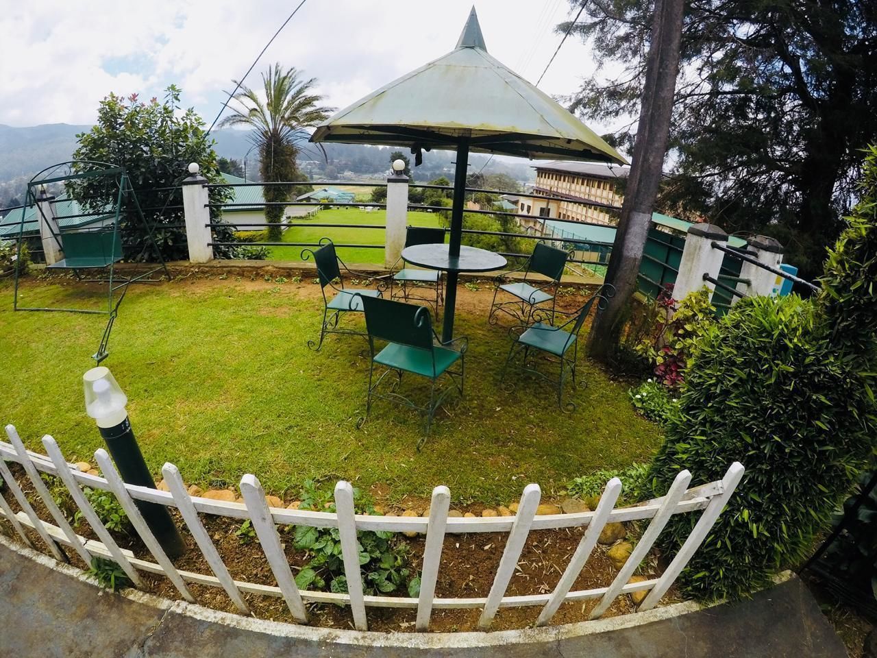A garden area with a gazebo, a white picket fence, and a view of the surrounding landscape.