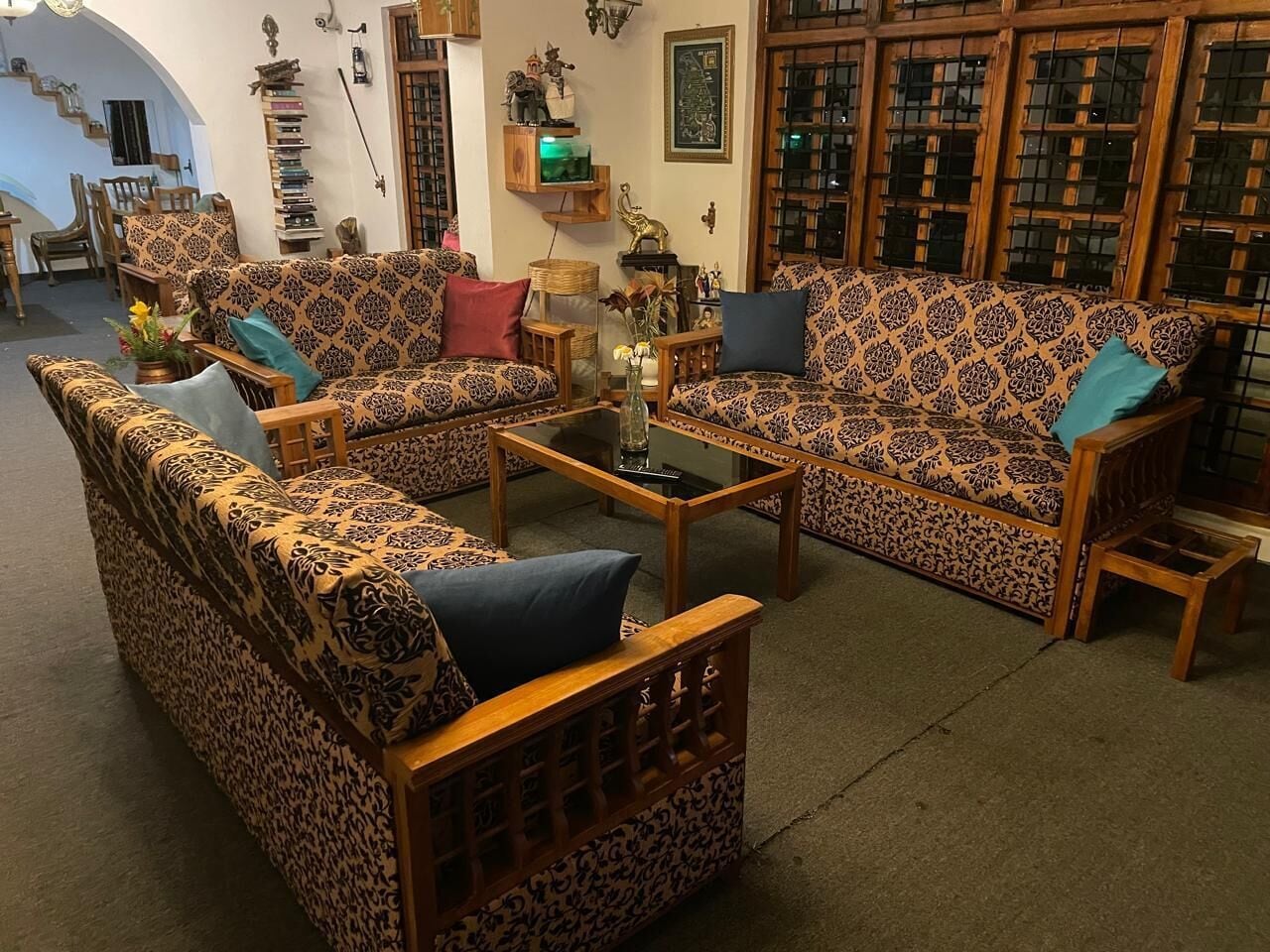 Un salon avec des canapés à motifs, une table basse et une bibliothèque.
