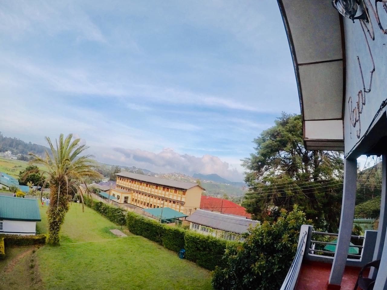 Vista de un edificio con techo verde, rodeado de vegetación y colinas al fondo.