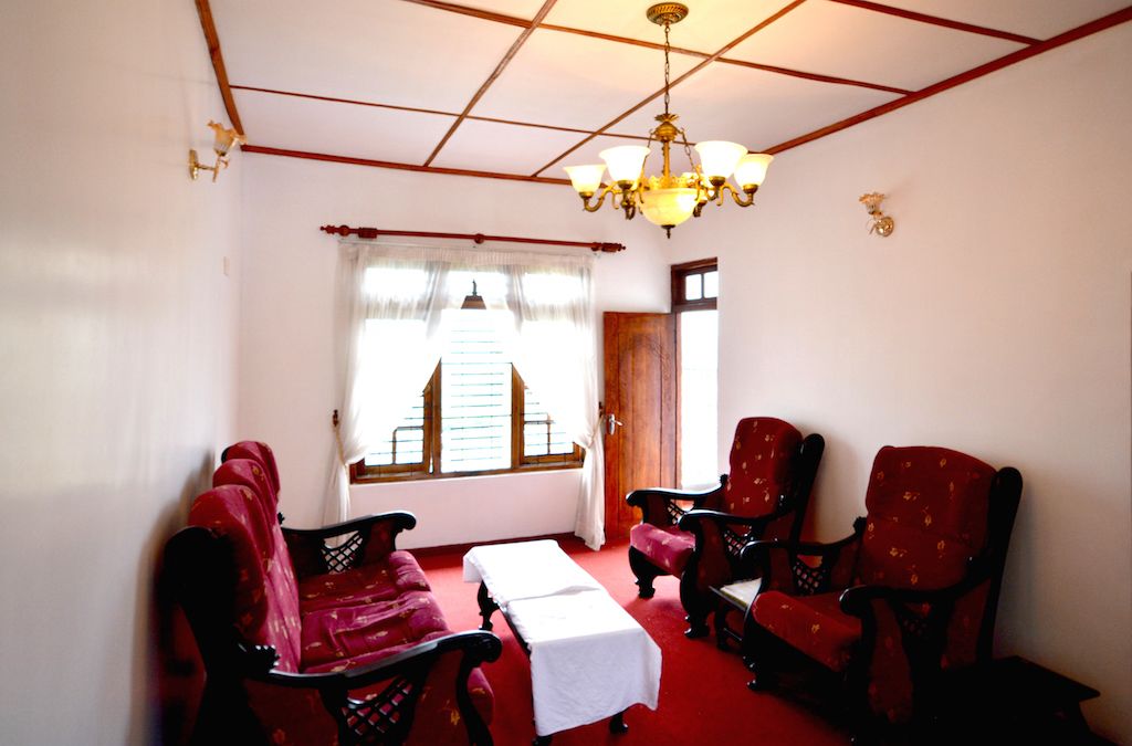 A room with a red carpet, a white table, and four red upholstered chairs.