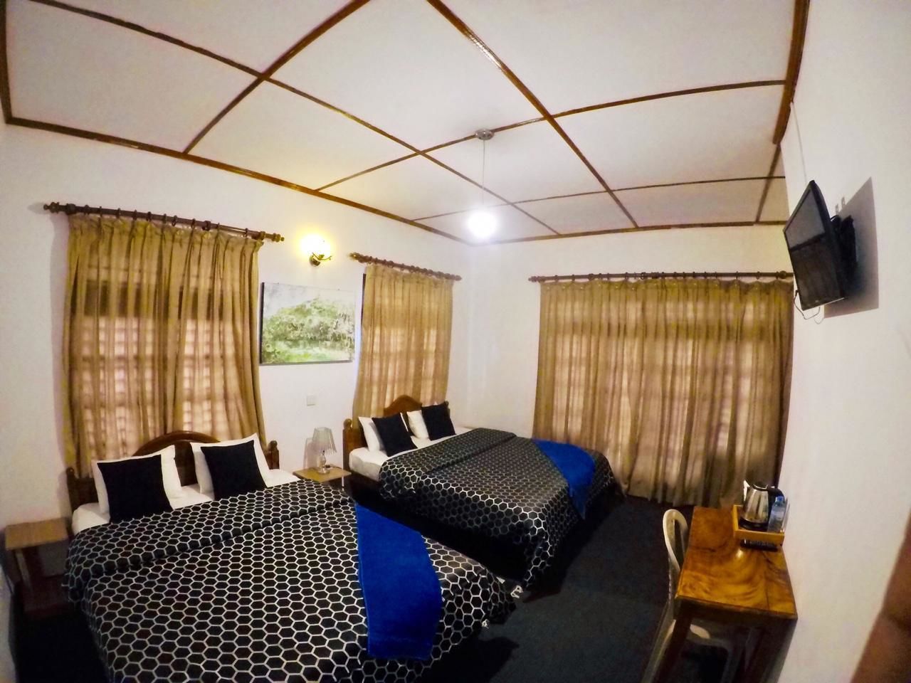 A hotel room with two beds, a desk with a chair, a television, and curtains.