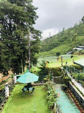 Un jardín exuberante con un sendero, un pabellón y vistas a un paisaje montañoso.