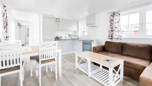 A modern, open-plan living area with a kitchen, dining table, and sofa.