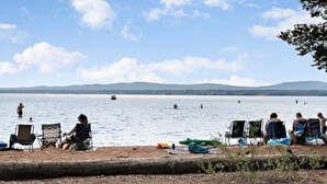 A lakeside beach with people swimming and relaxing.