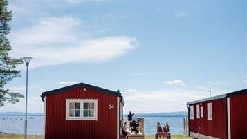 A red cabin with a window and the number 34, situated by a body of water.