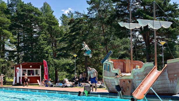 A swimming pool with a ship-shaped slide and a lifeguard station.