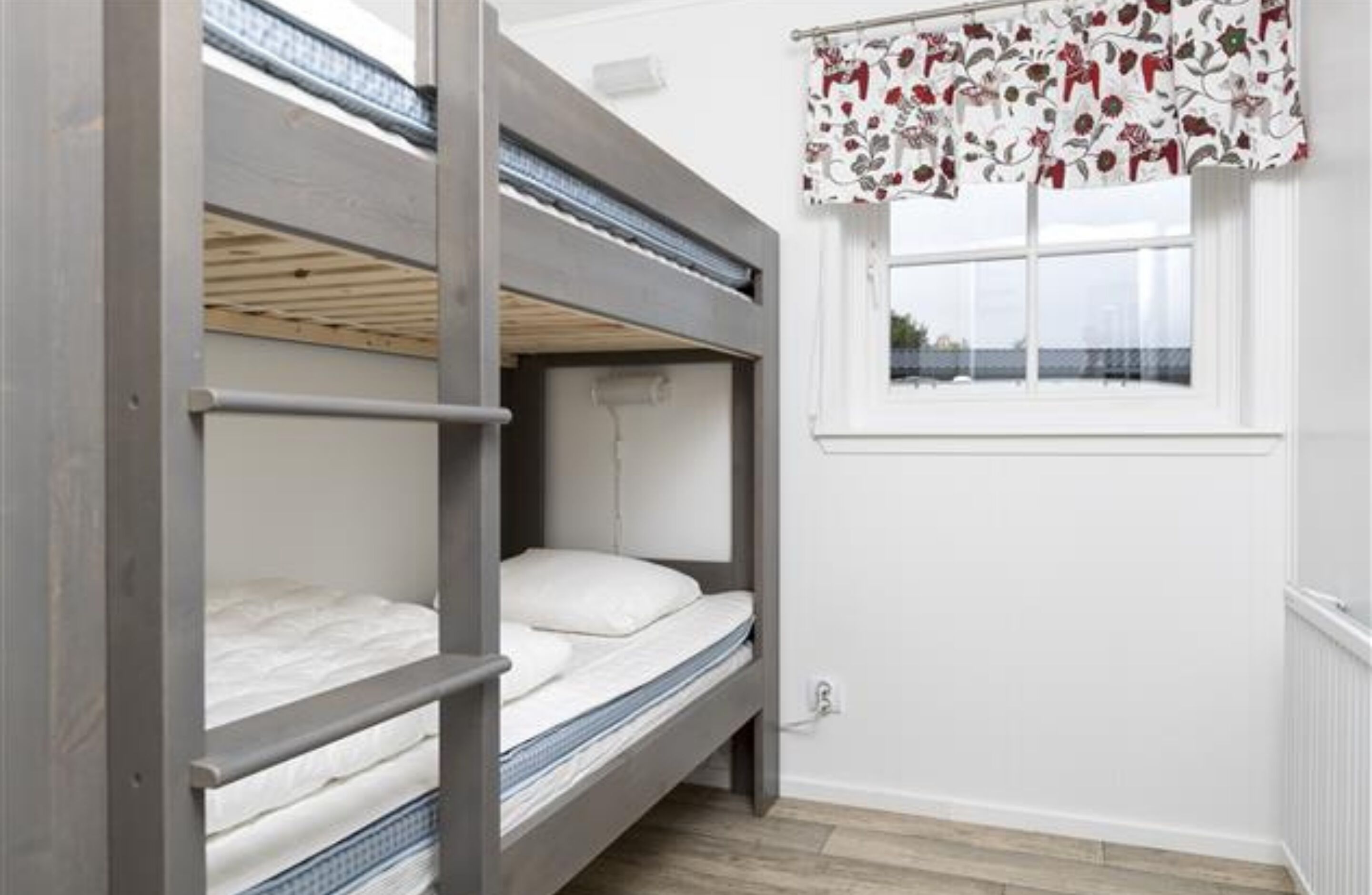 A bunk bed room with a window and a curtain.