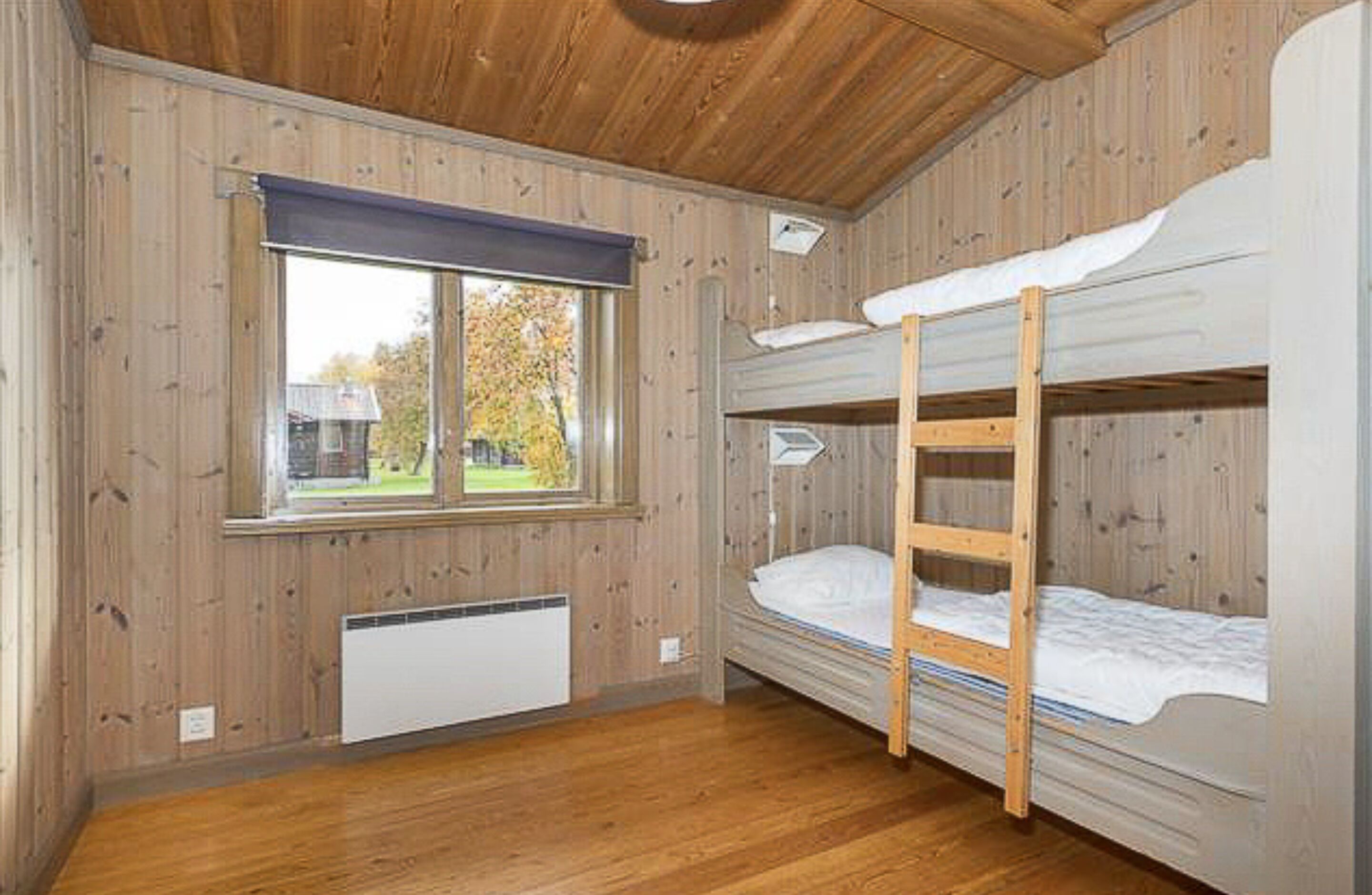 A bunk bed room with wooden walls and a window.