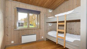 A bunk bed room with wooden walls and a window.