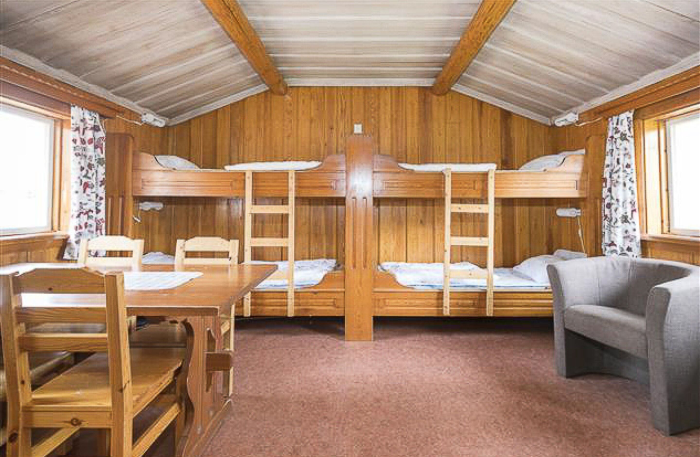 Une cabine avec des lits superposés, une table en bois et un canapé.