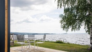 An outdoor deck with a table and chairs overlooking a body of water.