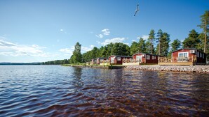 A lakeside cabin area with clear water, wooden docks, and red cabins.