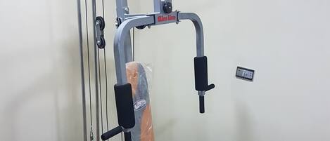 A gym with a pull-up bar, weight stack, and bench.