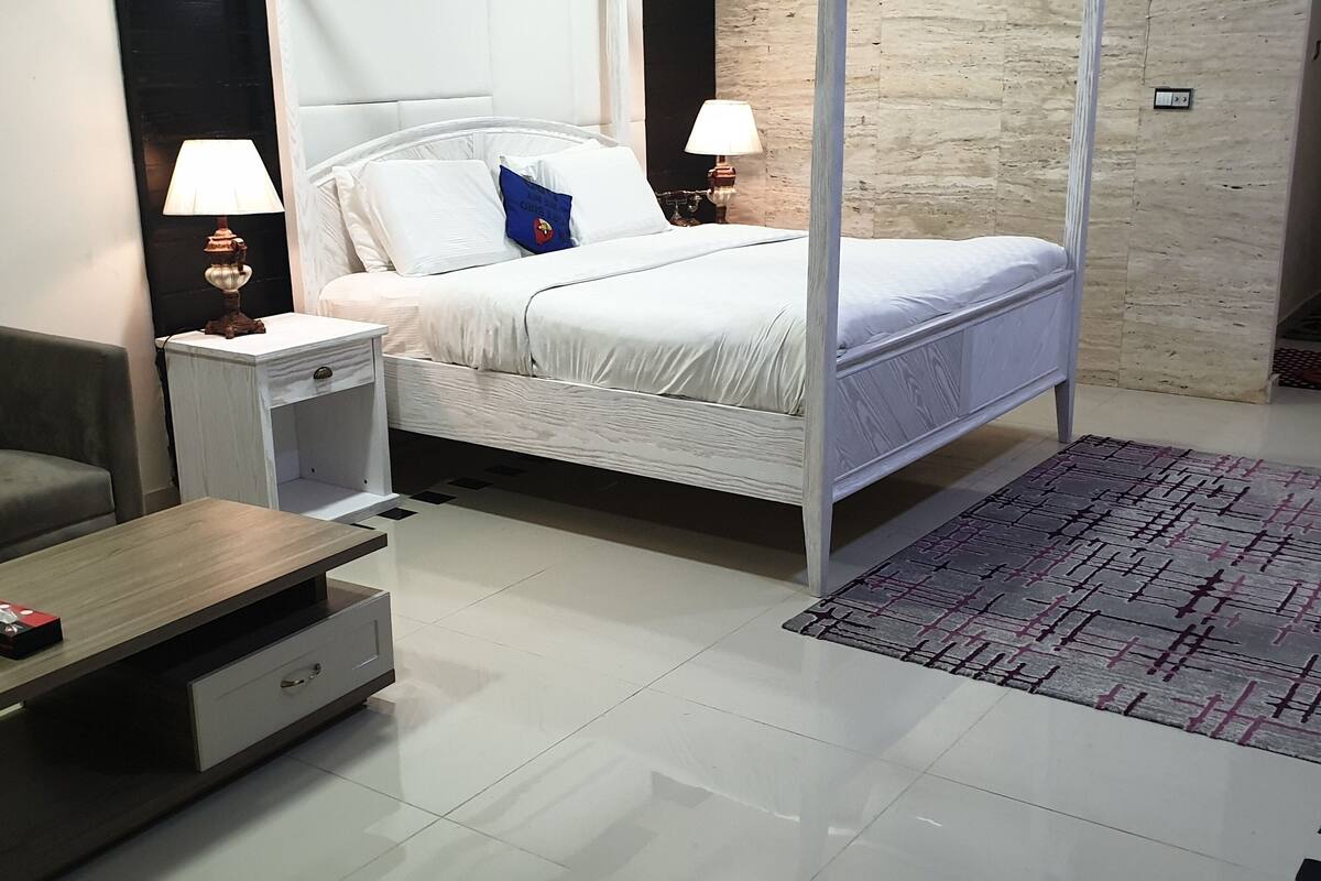 A modern bedroom with a bed, bedside tables, a nightstand, a sofa, and a coffee table.