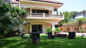 A two-story building with a balcony, outdoor seating area, and a well-maintained lawn. - Gofas Lodge (Islamabad)