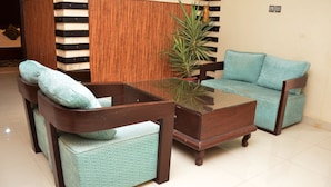 A modern living room with a glass coffee table, two matching sofas, and a wooden side table. - Gofas Lodge (Islamabad)