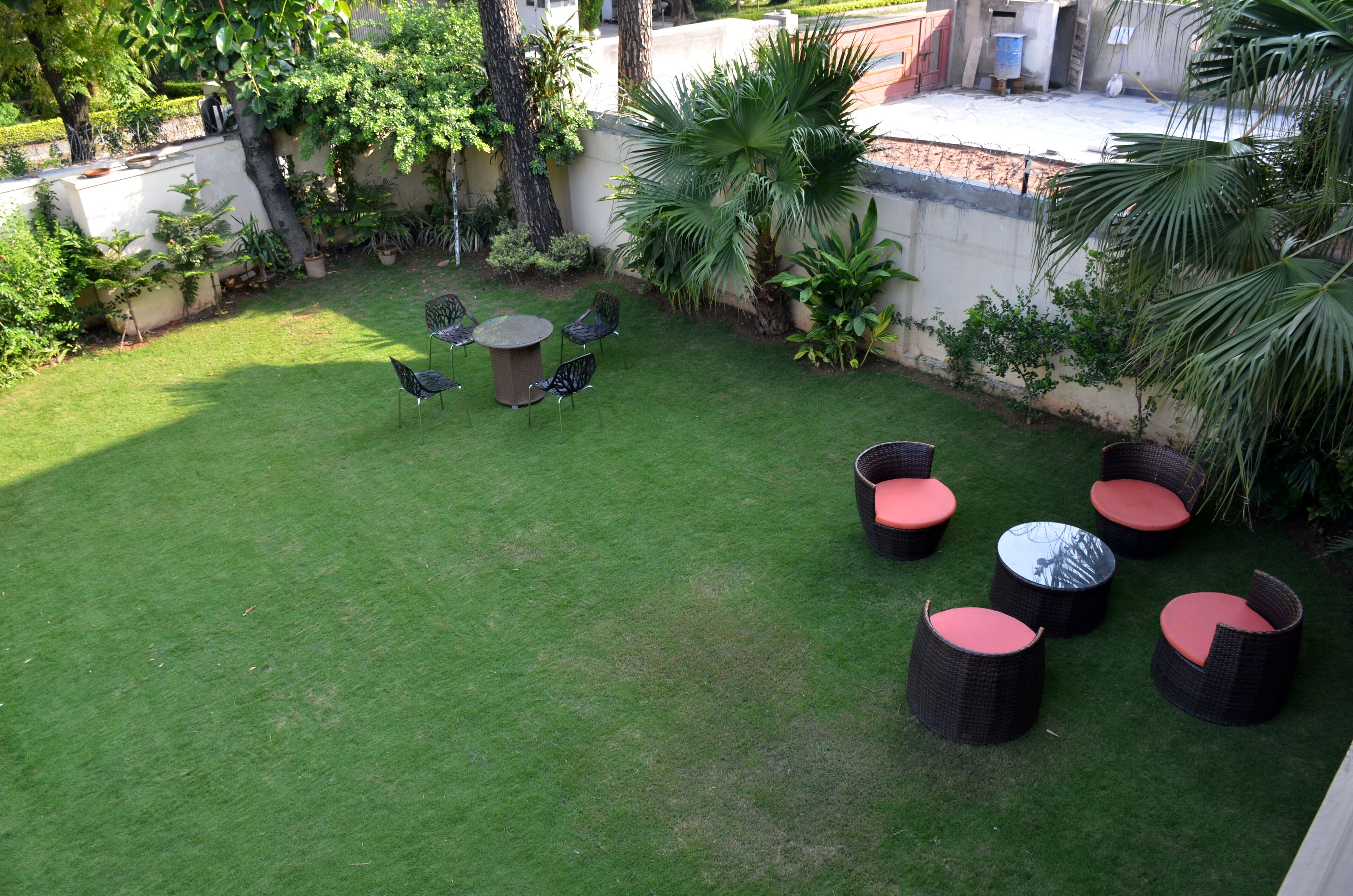 A patio area with a lawn, seating, and potted plants.