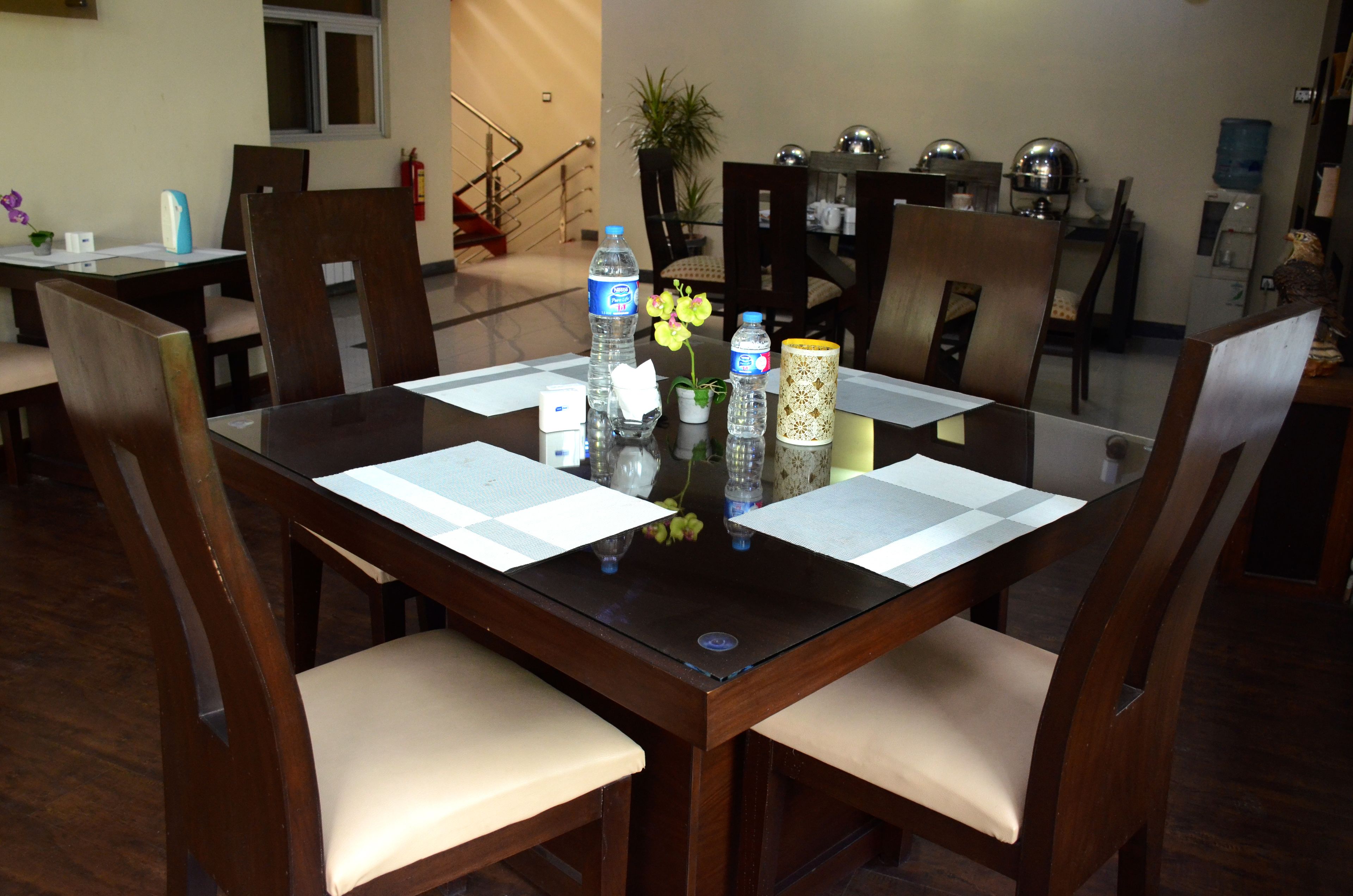 A dining table with chairs, water bottles, a vase with flowers, and papers on the table.