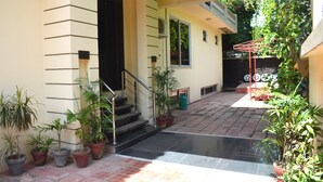 A covered outdoor area with potted plants, a staircase, and a red drying rack. - Gofas Lodge (Islamabad)