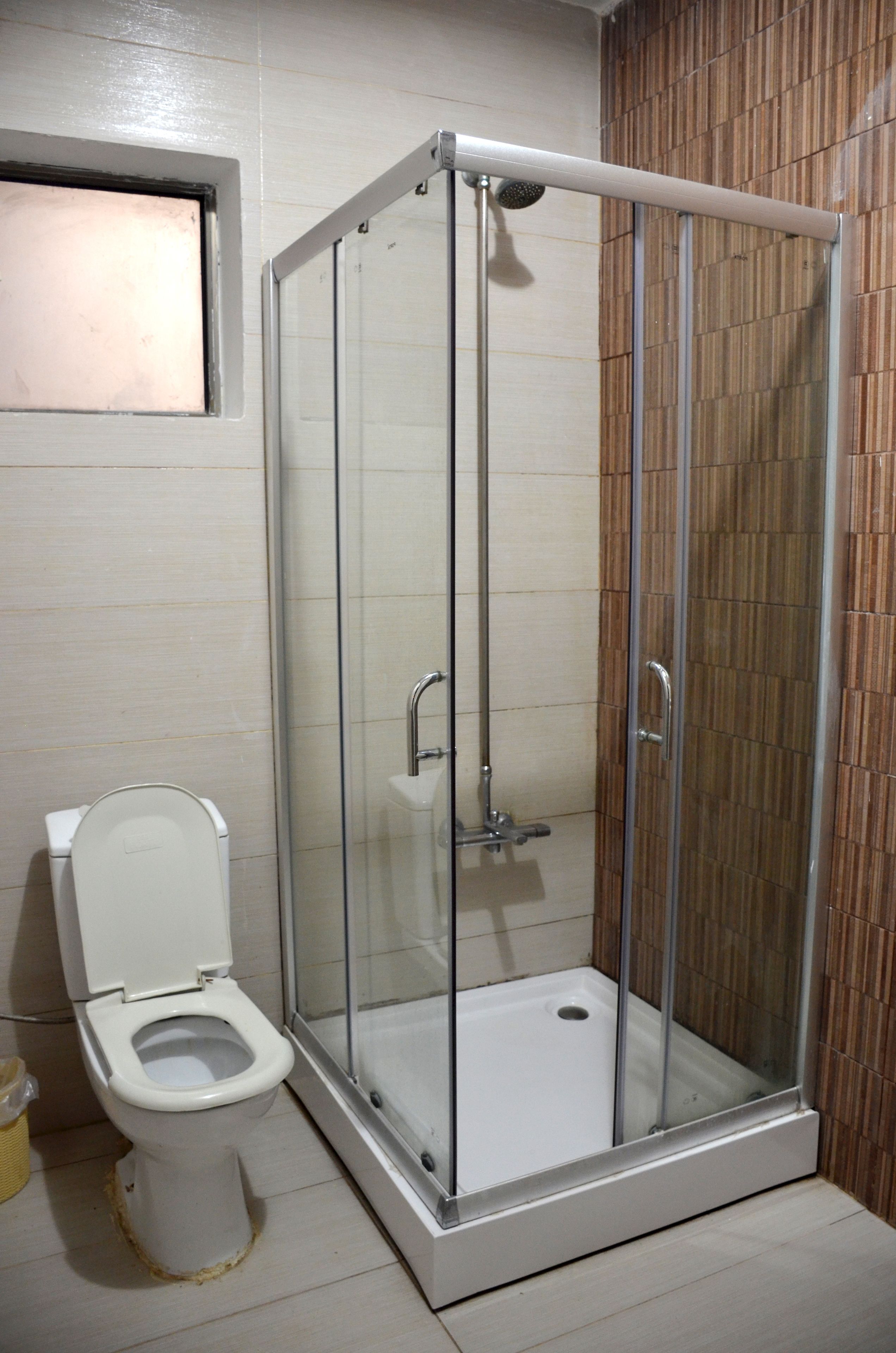Ein Badezimmer mit Duschkabine, Toilette und einer Wandverkleidung aus Holz.