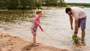 Una persona y un niño pescan junto a un lago.