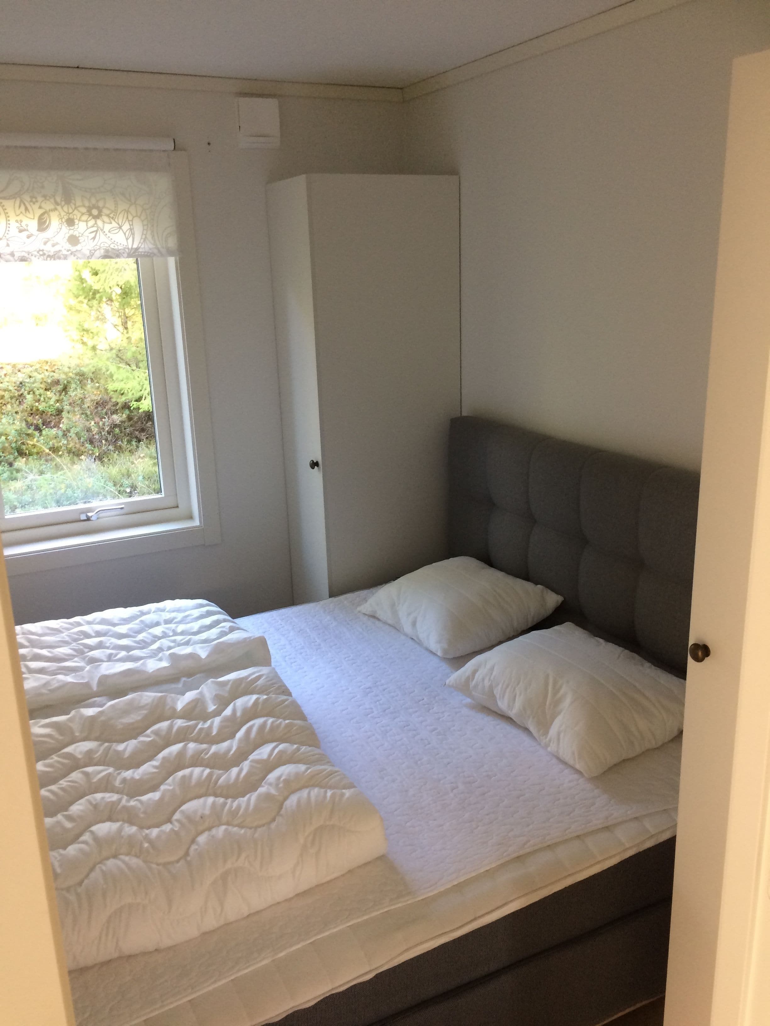 Un dormitorio con cama, ventana y armario.