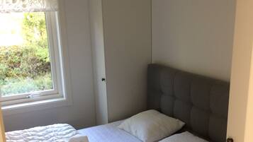 Un dormitorio con cama, ventana y armario.