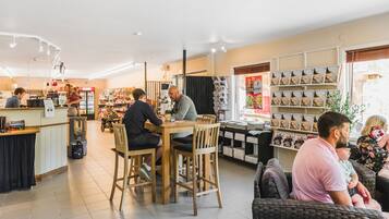 Een boekwinkel met houten tafels en stoelen, een balie en boeken- en tijdschriftenrekken.